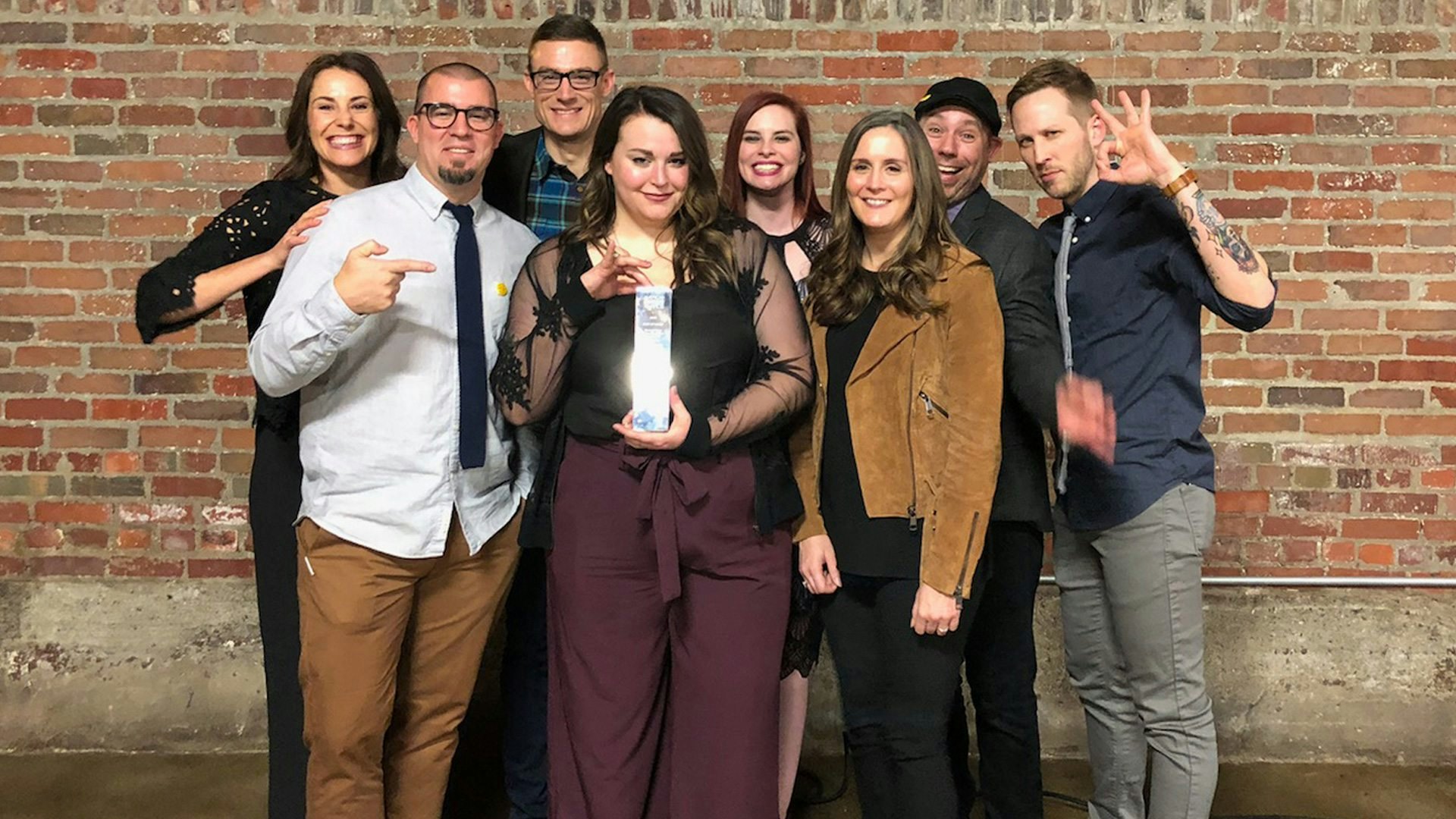 group of element three employees holding up addy award